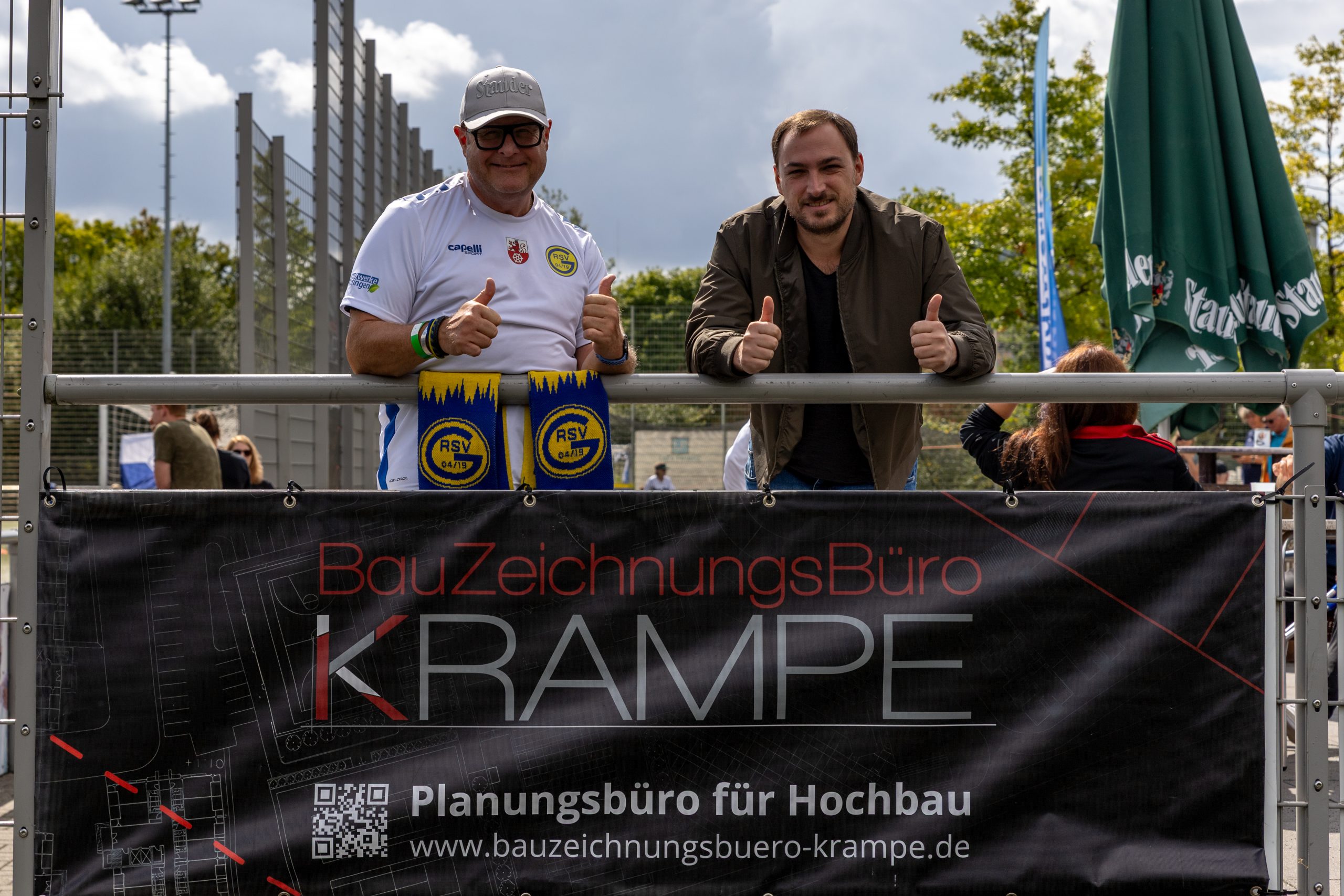 Tobias Krampe und Mirco Köstring stehen vor der Werbebande Der Firma Tobias Krampe Tobias Krampe und Mirco Köstring stehen vor der Werbebande Der Firma Tobias Krampe